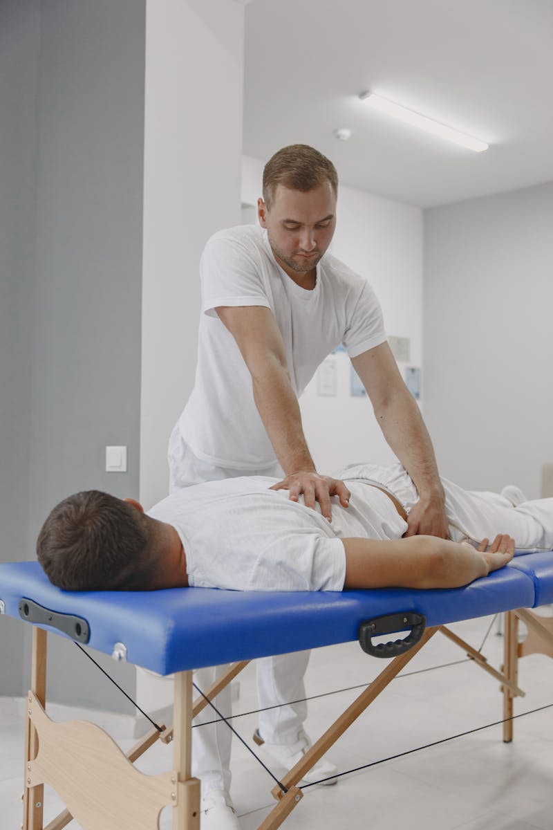 Man in White Crew Neck T-shirt Performing Massage Therapy on Man