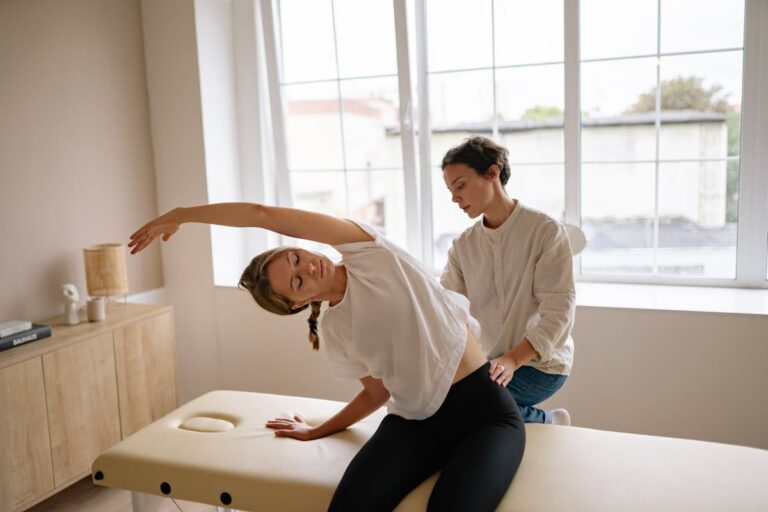 A woman receives a therapeutic massage and stretching on a massage table indoors.