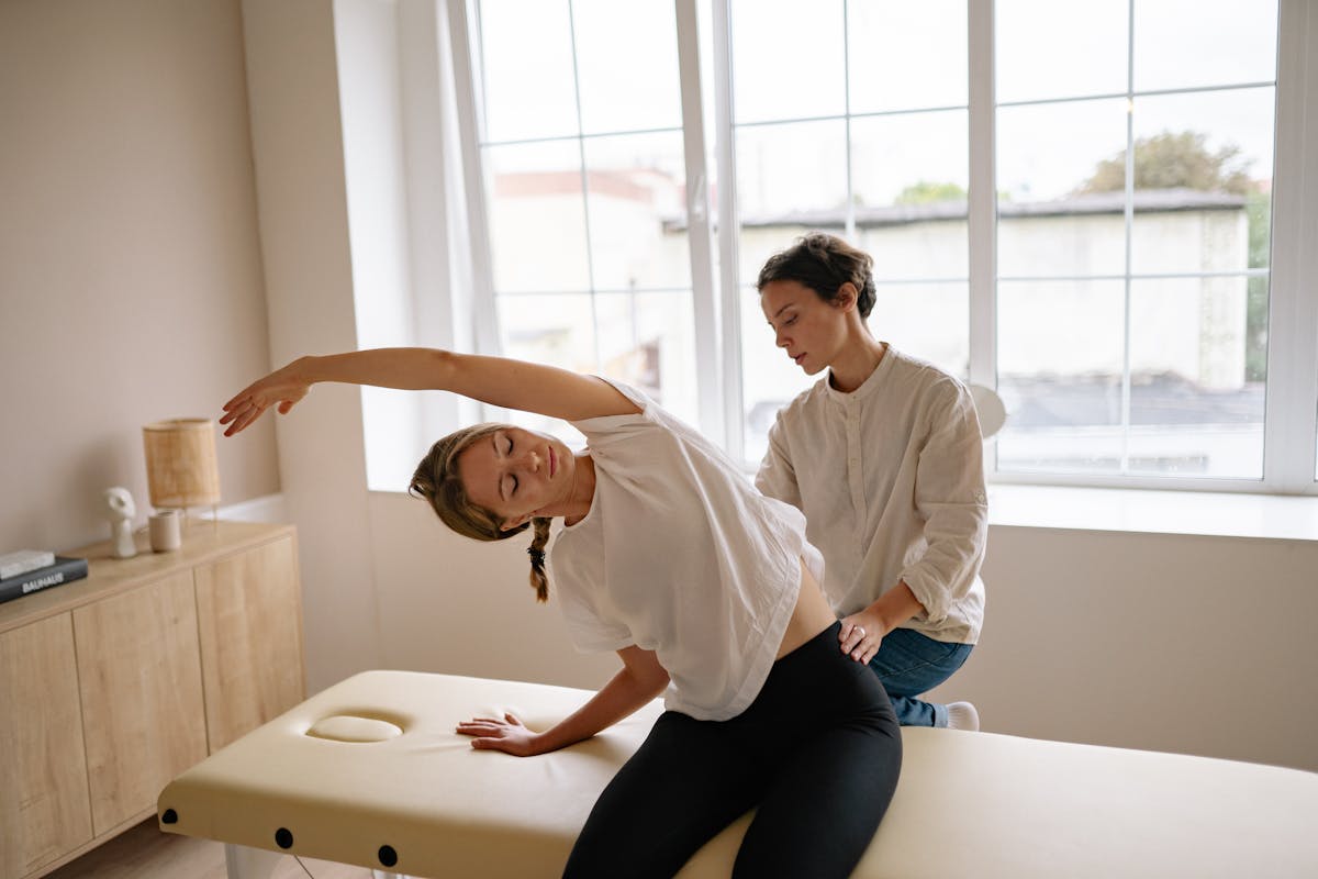 A woman receives a therapeutic massage and stretching on a massage table indoors.