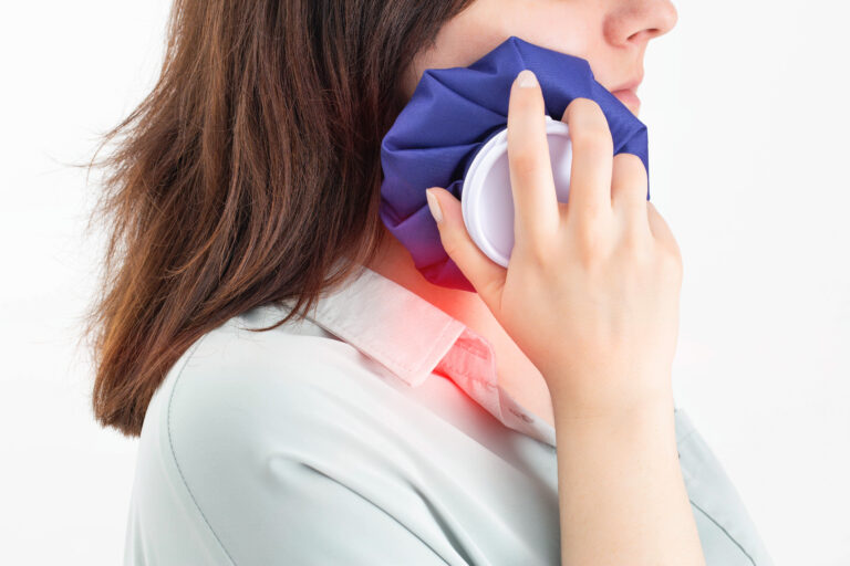 A girl attaches a medical bag with cold to the swelling on her cheek after removing a wisdom tooth. Concept for pain relief and inflammation in dentistry with the help of cold, pulpitis